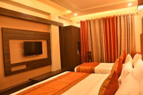 a hotel room with two beds and a flat screen tv at Hotel Abhinav International in Varanasi