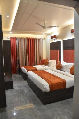 two beds in a hotel room with red curtains at Hotel Abhinav International in Varanasi