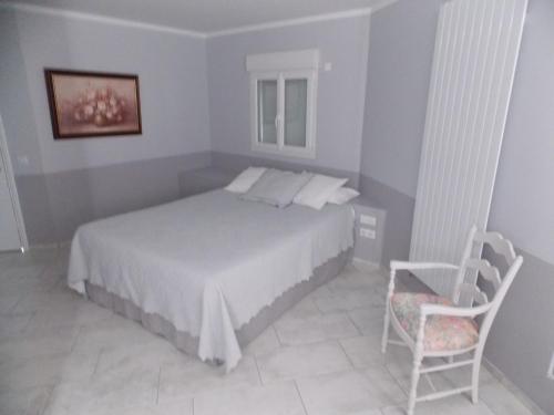 a bedroom with a white bed and a chair at Au Relais Provencal in Bagnols-en-Forêt