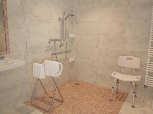a bathroom with a shower with two chairs and a sink at Au Relais Provencal in Bagnols-en-Forêt