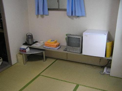 een keuken met een koelkast en een magnetron bij Ikawa Ryokan in Hiroshima