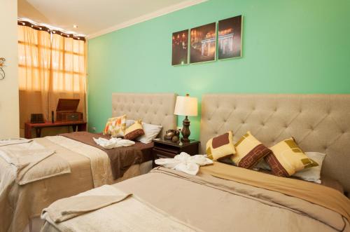 two beds in a room with blue walls at Hotel Vintage "Casa las Flores" in Quetzaltenango