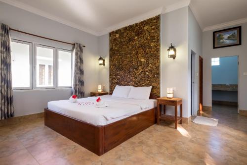 a bedroom with a bed and a stone wall at Kep Bungalows in Kep