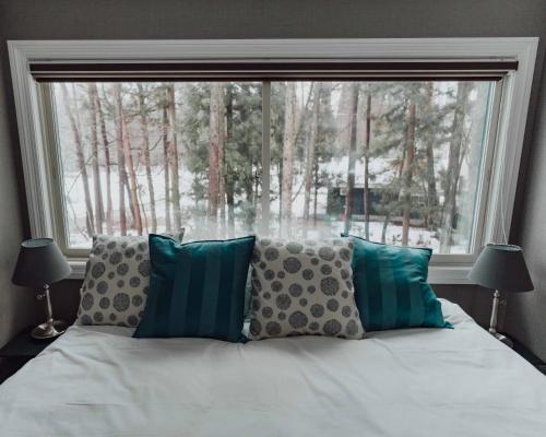een bed met kussens voor een groot raam bij Ski-in, Ski-out Hatsuyuki Apartments in Hakuba