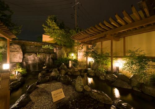 a pond in a garden at night with lights at Oike Hotel in Fujikawaguchiko