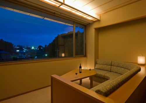 a living room with a couch and a table and a window at Oike Hotel in Fujikawaguchiko