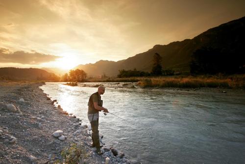 a man standing in a river holding a fishing rod at Relais Del Nazionale in Vernante