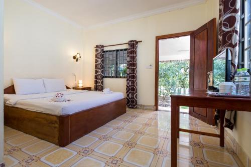 a bedroom with a bed and a desk and a window at Kep Bungalows in Kep