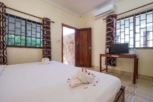a bedroom with a bed and a tv and windows at Kep Bungalows in Kep