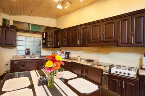 a kitchen with wooden cabinets and a table with a vase of flowers at Hotel Vintage "Casa las Flores" in Quetzaltenango