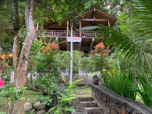 a garden with a house in the background at Kupu Kupu Garden Guest House & Cafe in Bukit Lawang