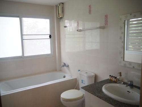 a bathroom with a white tub and a sink and a toilet at BAANTAI HOMESTAY in Chumphon