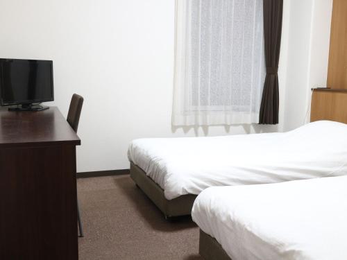 a hotel room with two beds and a flat screen tv at Hotel Sun Plaza Sakai in Sakai