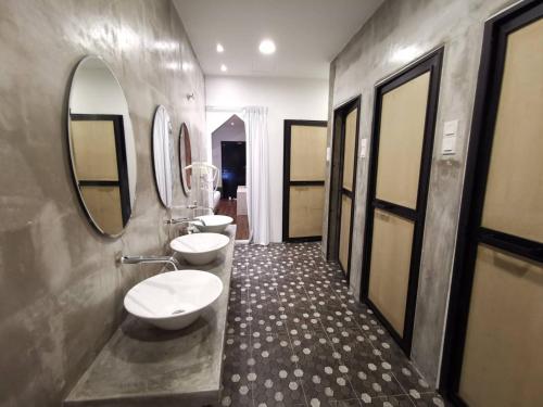 a bathroom with two sinks and two mirrors at Iconic Suites & Pods Hotel in Ipoh