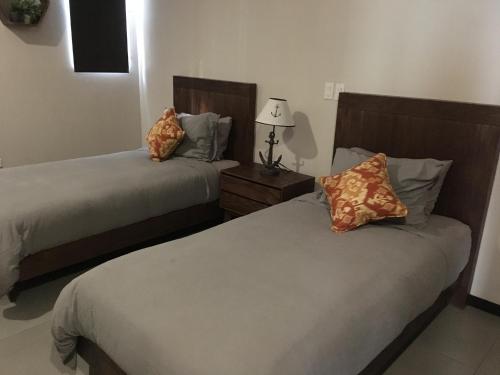 a bedroom with two beds and a table with a lamp at El Refugio in Ensenada