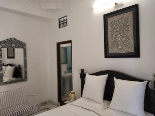a bedroom with a bed with white pillows and a mirror at Hotel Mewari Villa PURE VEG in Udaipur