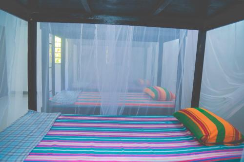 uma cama com almofadas coloridas num quarto em Hikka Surf Hostel em Hikkaduwa