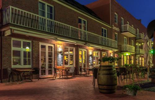 a patio with tables and chairs in front of a building at Strand-Hotel Seenelke in Wilhelmshaven