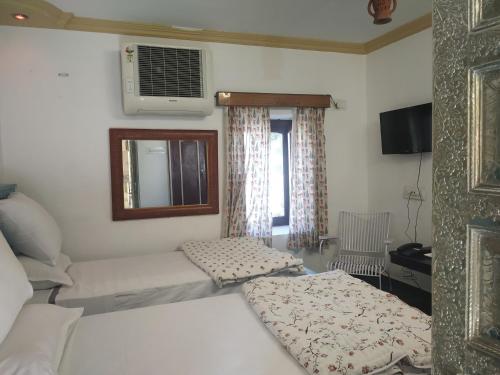 a small bedroom with two beds and a window at Hotel Mewari Villa PURE VEG in Udaipur