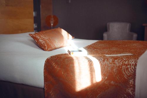 a bed with white sheets and an orange pillow at Villa Les Bains in Houlgate