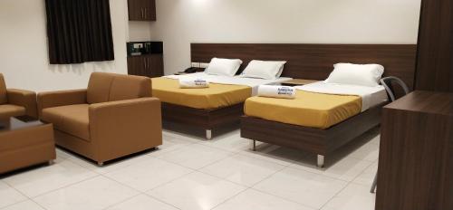 a hotel room with two beds and a couch at Hotel Karuna Residency in Mangalore