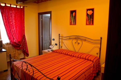 a bedroom with a bed with a red comforter at Agriturismo Monbertola in Govone