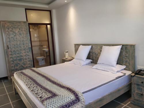 a bedroom with a large bed with white sheets and pillows at Hotel Mewari Villa PURE VEG in Udaipur
