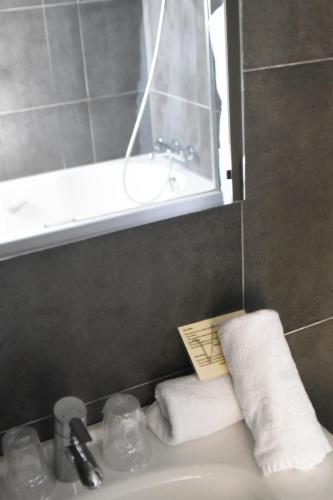 a bathroom with a sink and a mirror and towels at Villa Les Bains in Houlgate