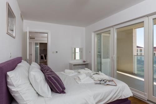 a bedroom with a white bed and a large window at Apartments Nav in Dubrovnik