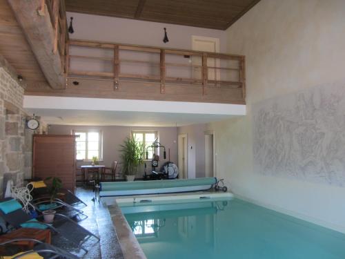 a large swimming pool in a living room with a table at Le relais des deux tours in Brémondans