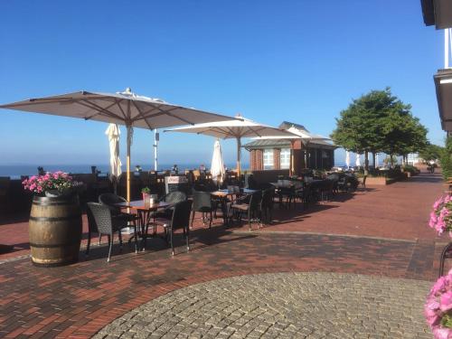 a patio with tables and chairs and umbrellas at Strand-Hotel Seenelke in Wilhelmshaven