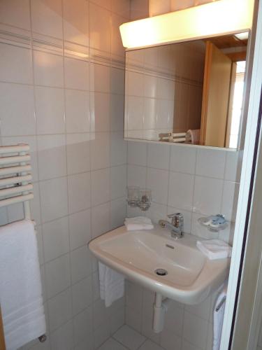 a white bathroom with a sink and a mirror at Berghaus Männlichen in Grindelwald