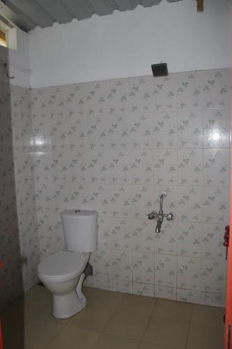 a bathroom with a white toilet in a room at Johnson's Homestay With Pool & Ecohouseboat near town beach in Alleppey
