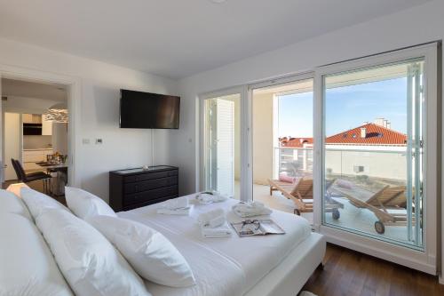 a white bed in a room with a large window at Apartments Nav in Dubrovnik