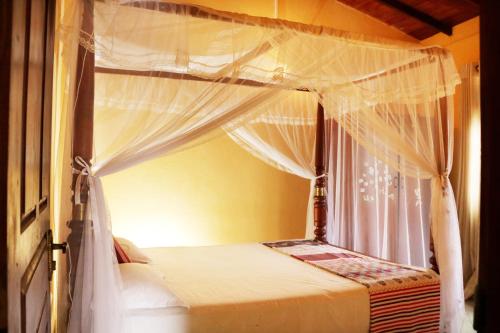 una camera con letto a baldacchino e tende bianche di Ariyadasa Guest House a Galle