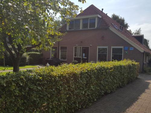 a brick house with a hedge in front of it at Vakantiehuis Aangenaam - Olde Horst in Diever