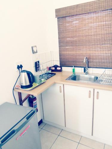 a small kitchen with a sink and a refrigerator at Kairos Cottage B&B in Lüderitz