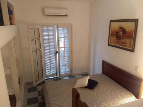 a bedroom with a bed and a door with a window at Suítes Família Mateus in Ubatuba