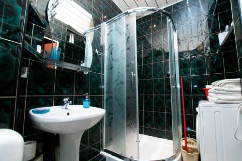 La salle de bains est pourvue de carrelage noir, d'un lavabo et d'une douche. dans l'établissement Apartament Gosia, à Rogowo