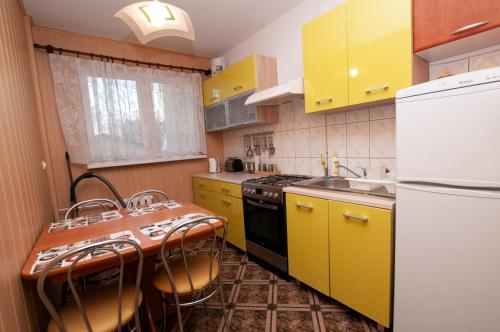 kuchnia z żółtymi szafkami i stołem z krzesłami w obiekcie Apartament Gosia w Rogowie