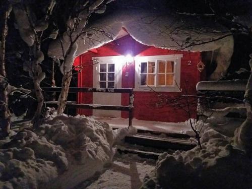 a house covered in snow with a light on it at Bakkakot 2 - Cozy Cabins in the Woods in Akureyri