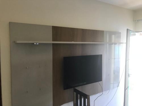 a flat screen tv on a wall in a room at Casa com piscina, wifi e churrasqueira em unamar. in Tamoios