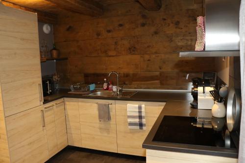 une cuisine avec des armoires en bois et un évier dans l'établissement La Maison des Charpentiers, à Zimmerbach