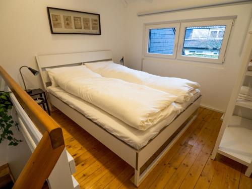Bett mit weißer Bettwäsche in einem Zimmer mit Fenster in der Unterkunft Gemütliche Ferienwohnung im Reihenhaus in Hochheim am Main
