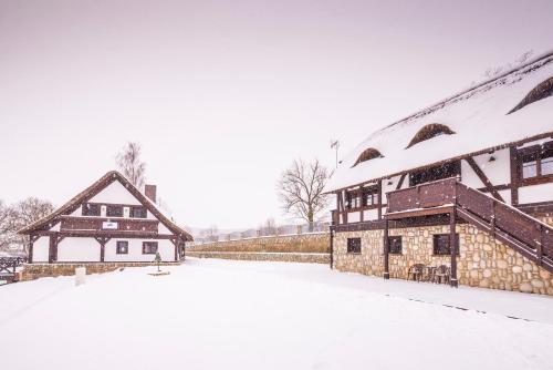 a house and a barn covered in snow at Ranczo Pod Strzechą in Stara Kamienica