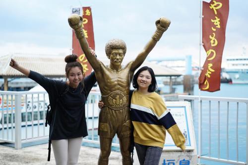 two women standing next to a statue of a boy at The BREAKFAST HOTEL PORTO Ishigakijima in Ishigaki Island