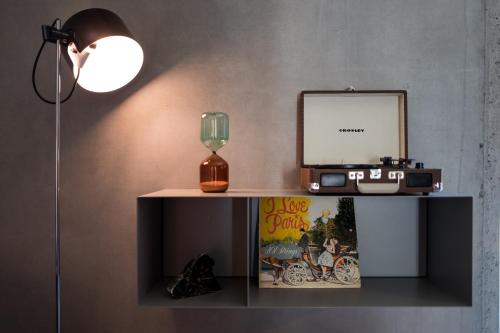 a table with a lamp and a clock and a glass at Das Eckert - Lifestyle Design Hotel & Fine Dining bei Basel (Grenzach) in Grenzach-Wyhlen