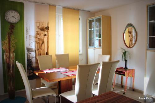 a dining room with a table and chairs and a clock at Donau Pension in Tuttlingen