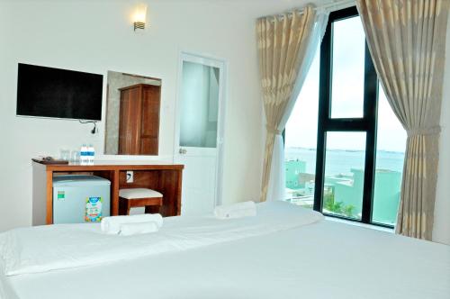 Schlafzimmer mit einem Bett, einem Schreibtisch und einem Fenster in der Unterkunft Khách sạn Trâm Anh in Quy Nhon