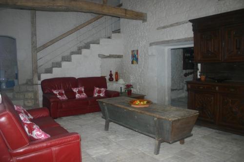 a living room with a red couch and a table at L'ancienne cave in Prinçay